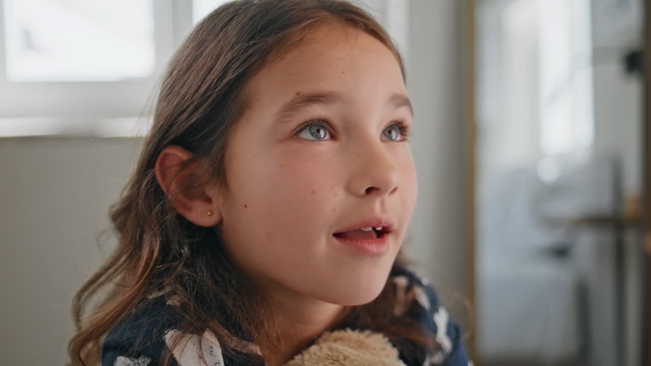 Closeup cute toddler talking at bedroom. Funny little child embracing teddy bear