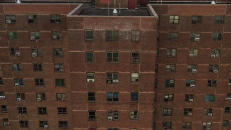 inclinación aérea dramática hacia arriba a lo largo del eje vertical del edificio del proyecto de vivienda en east harlem, nueva york, temprano en la mañana, revelando el horizonte
