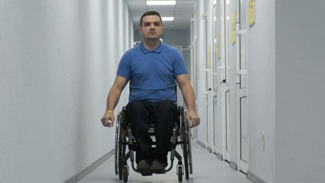 un hombre en silla de ruedas conduce por el pasillo. una persona con discapacidad se mueve por el hospital.