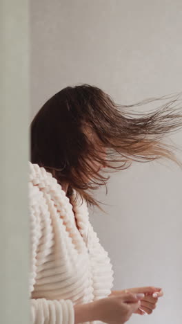 mujer se mueve a la música en el reflejo del espejo en el inodoro. joven mujer morena con el cabello mojado se divierte con la música después de tomar la ducha en cámara lenta