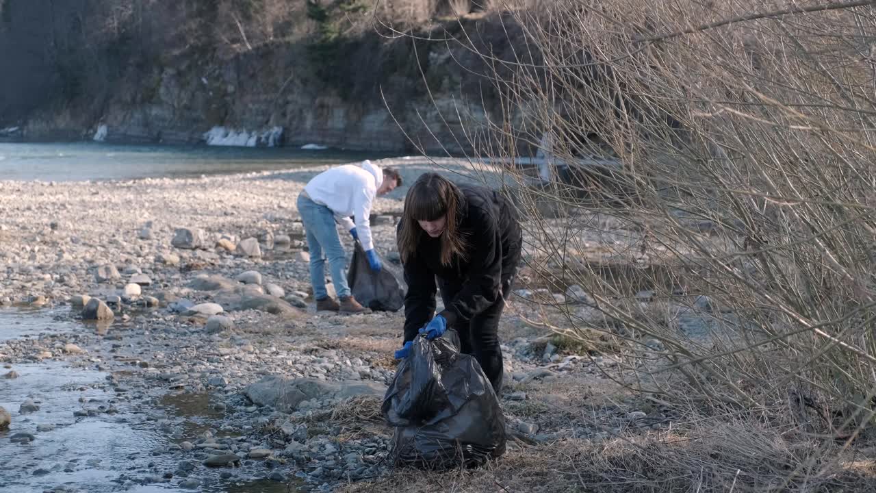Trabalho em equipe limpando plástico na praia. Voluntários recolhem lixo em um saco de lixo. Conceito de poluição plástica e problema ambiental. Limpeza voluntária da natureza de plástico. Preservando o planeta.