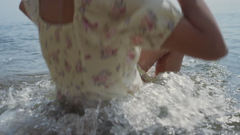 Young-woman-falling-down-in-ocean-water-holding-hat.-Girl-slipped-on-wet-sand.