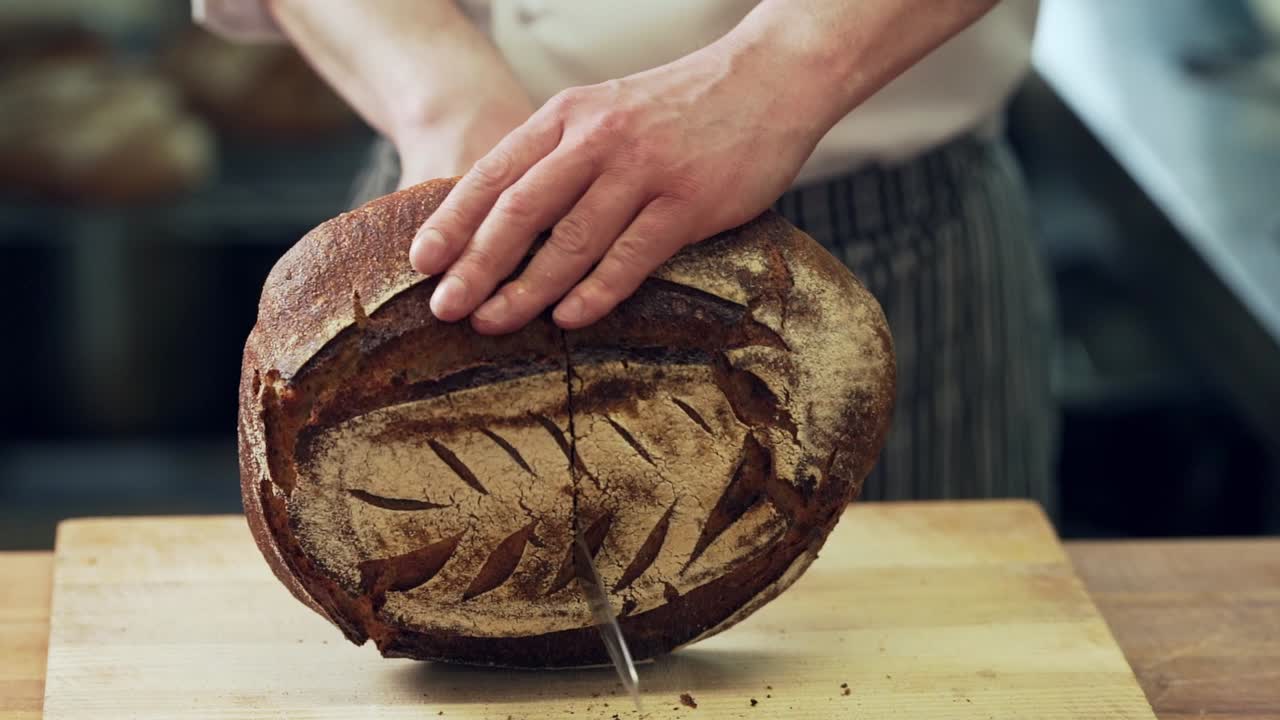 closeup, baker's hands cut home-made rye bread