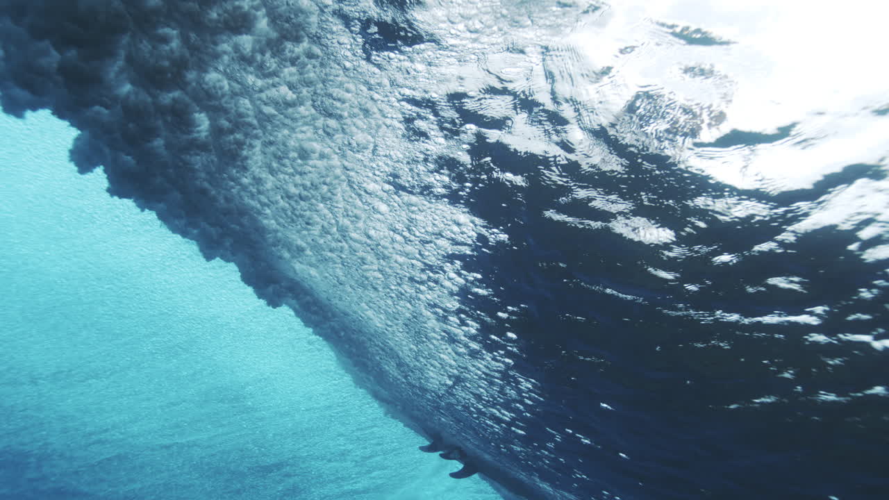 Underwater tracking follows vortex of open ocean wave at Cloudbreak Fiji crashing with foam and whitewash