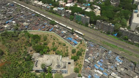 Drohne-Folgt-Fahrendem-Zug-In-Der-Nähe-Des-Slums-Dharavi-In-Mumbai