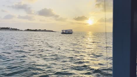 Vista-De-La-Puesta-De-Sol-En-Maldivas:-Vista-Al-Mar-Y-Quietud-Serena-Del-Horizonte-Al-Atardecer-De-La-Isla,-Con-Un-Barco-Dhoni-Tradicional-A-La-Deriva-A-Lo-Largo-Del-Horizonte,-Experiencia-De-Escapada-Tropical-Perfecta