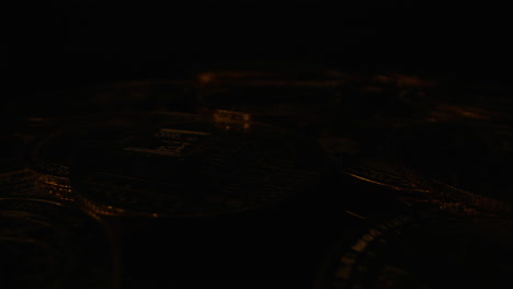 ethereum gold coins are illuminated by a flickering light against a dark background - close up, pullback shot