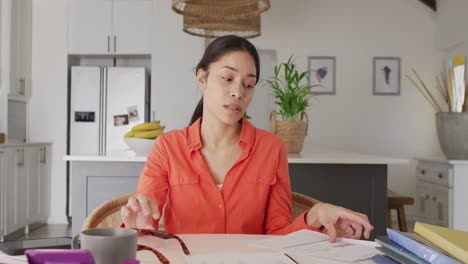 Portrait-of-biracial-woman-sitting-at-table-and-having-video-call