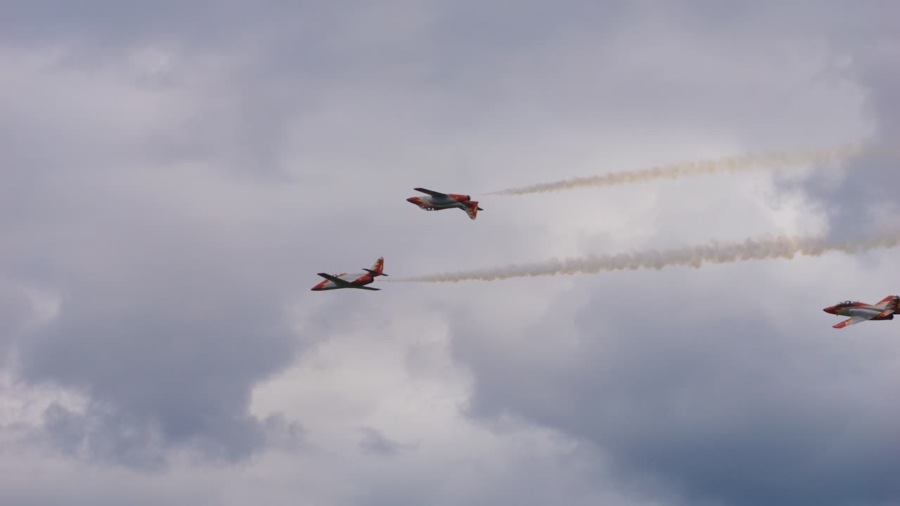 The Patrulla Aguila aerobatic team of the Spanish Air Force fly through the air with a stunt at Airpower. One is flying upside down in the air.