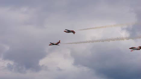 the patrulla aguila aerobatic team of the spanish air force fly through the air with a stunt at airpower. one is flying upside down in the air.