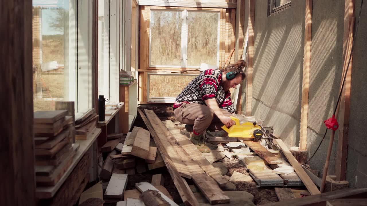 construcción de invernaderos - hombre en el trabajo cortando tablas de madera con una máquina de corte