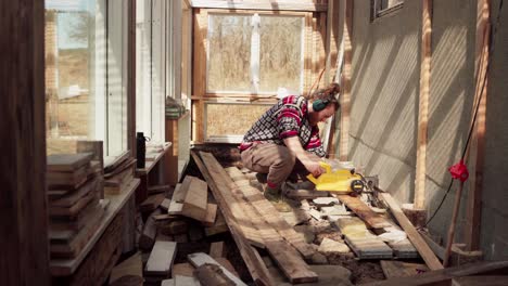 construcción de invernaderos - hombre en el trabajo cortando tablas de madera con una máquina de corte