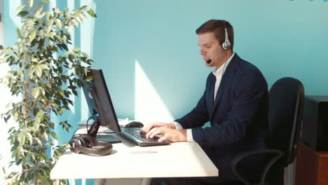 man working at a computer with a headset in an office