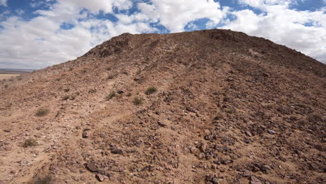 Volando-Por-Una-Colina-En-El-Desierto-De-Mojave-Hasta-La-Cima-Y-Luego-Bajando-Por-La-Empinada-Pendiente-Hasta-El-Suelo-Del-Desierto-En-Un-Dron-En-Primera-Persona---Cámara-Lenta