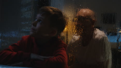 grandson and grandfather watching the rain