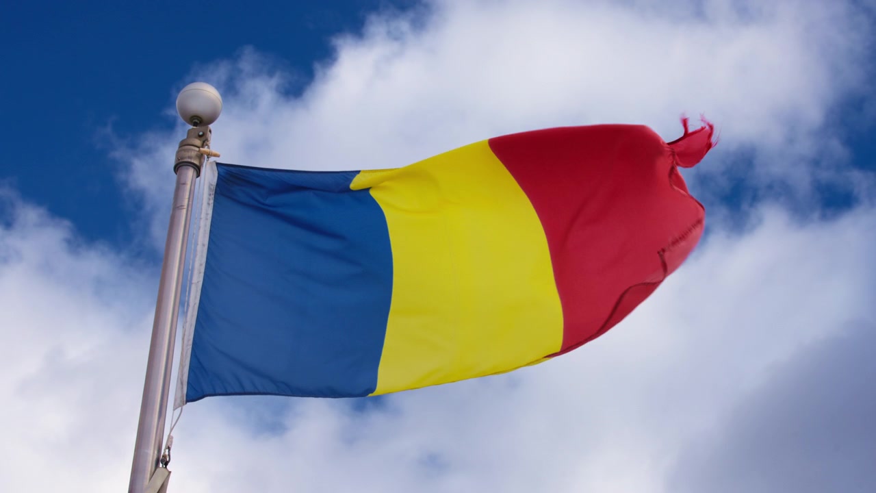 Bandiera della Romania che sventola al vento contro un cielo blu.