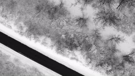 Look-up-drone-shot-from-a-empty-street-framed-by-a-winter-landscape-up-to-snow-covered-houses-of-a-little-idyllic-town,-calm-moment-in-times-of-the-pandemie