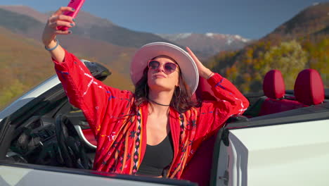 woman taking a selfie in a convertible car on a scenic mountain road trip