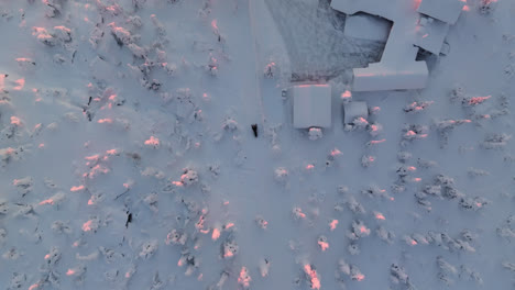 birds eye drone shot tracking skidoo passing a house, arctic sunrise in lapland