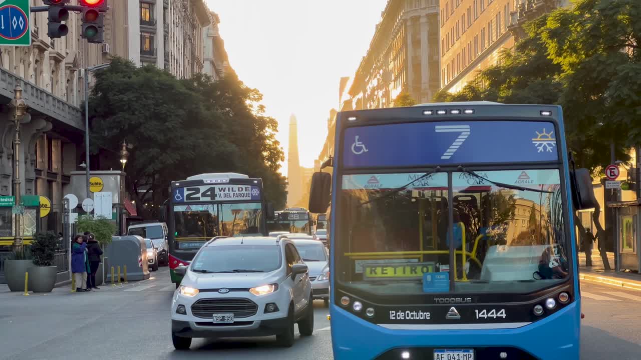 Buses and traffic on a bustling city street during sunset or sunrise in Buenos Aires