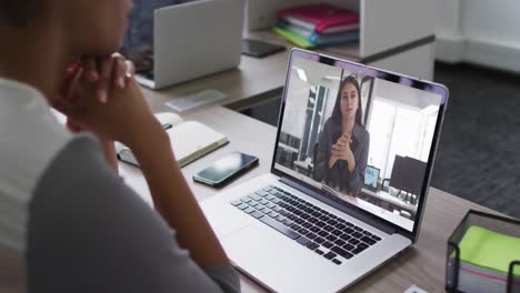 Mid-section-of-african-american-woman-having-a-video-call-with-female-colleague-on-laptop-at-office