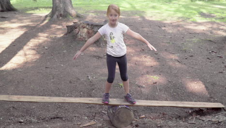 little girl plays on a wooden board in the forest, 4k