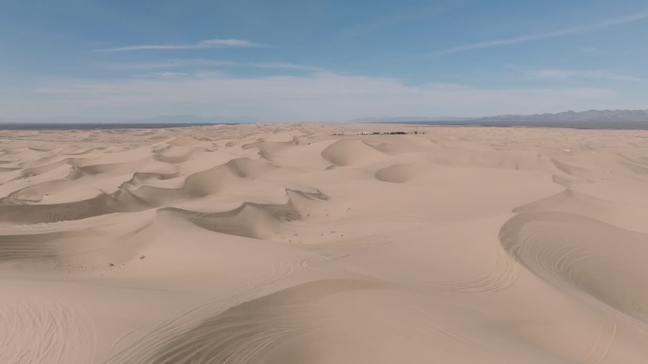 volando sobre una vasta e interminable extensión, toma aérea de dunas de arena del desierto con picos y crestas, cielos azules arriba