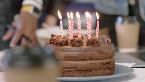 close up business people celebrating birthday party blowing candles on chocolate cake enjoying happy office celebration in cheerful workplace