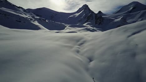 Drohne-Schwenkt-Langsam-Von-Backcountry-Skifahrern-Hinauf,-Die-Den-Hang-Hinaufsteigen,-Um-Einen-Weiten-Blick-Auf-Die-Berge-Freizugeben