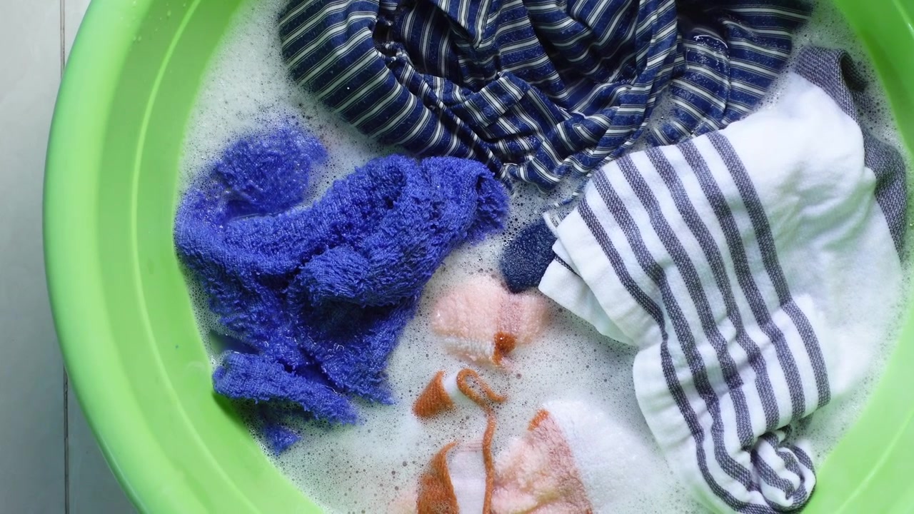 Kleding in de week in een groene teil met zeepwater.