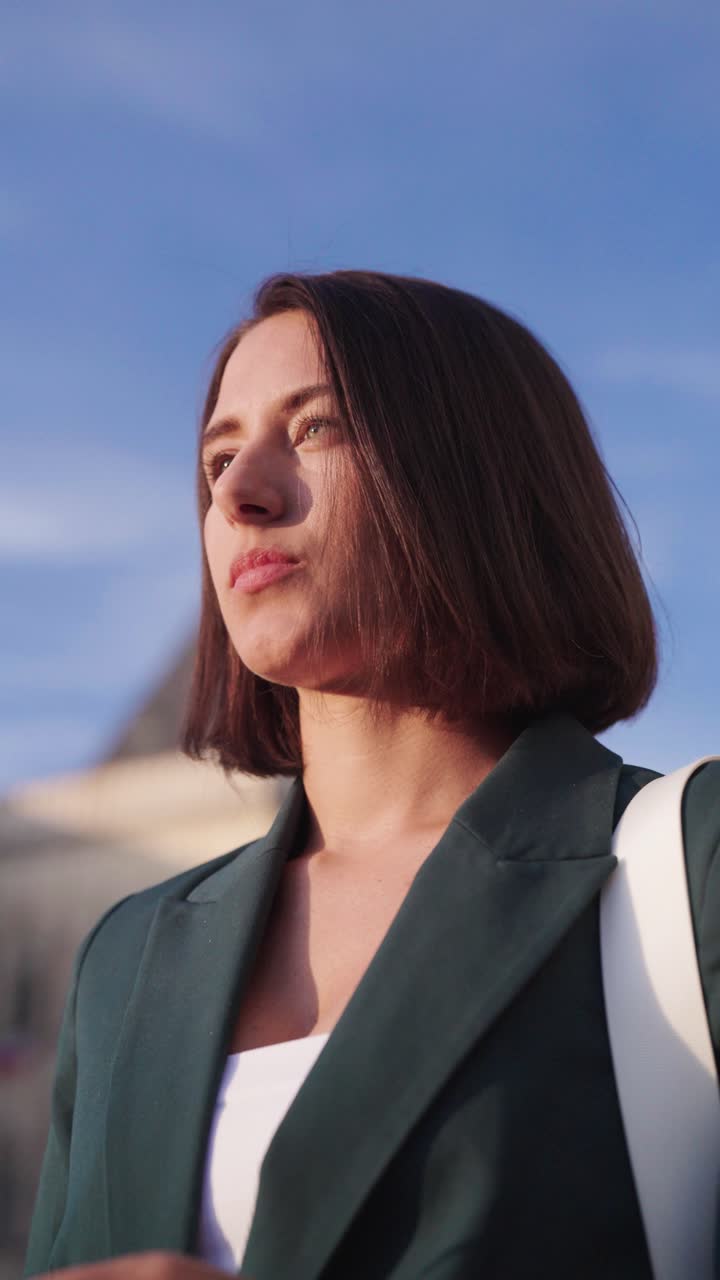 Vertical low angle close up of woman in bright daylight touch hair, Prague