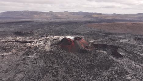 aerial drone moving close, icelandic volcanic crater with red lava rocks and steam rising, raw volcanic terrain and geology