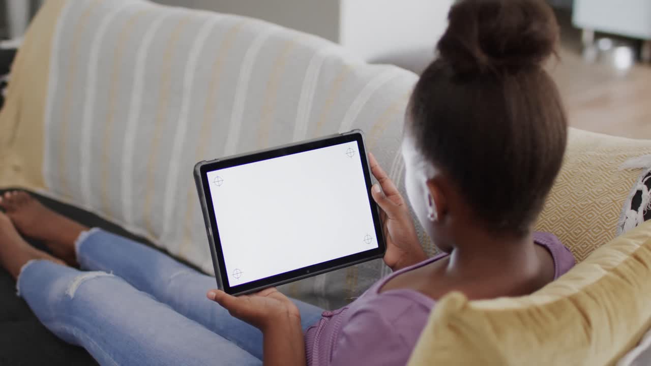African american girl sitting on sofa and using tablet with copy space, slow motion