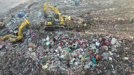 garbage dumpsite with workers and machinery