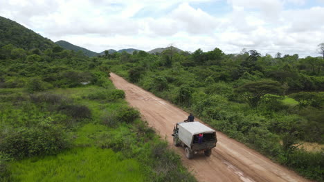 vista aérea de un camión que se mueve por un camino de tierra en un paisaje rural húmedo y verde, disparo de un dron