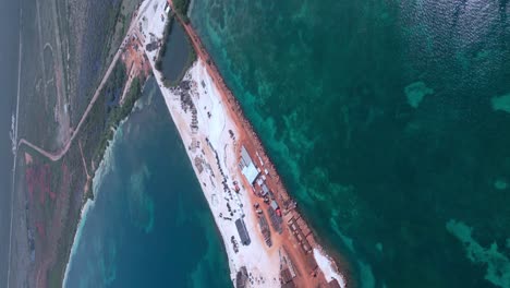 vertical high angle shot of large construction site surrounded by clear caribbean sea in summer - port cabo rojo in pedernales