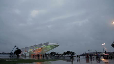 tomorrow museum museu do amanhã rainy day, guy cycling with umbrella, wide lateral shot