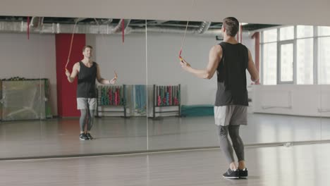 athlete man jumping on skipping rope at cardio training in gym club.