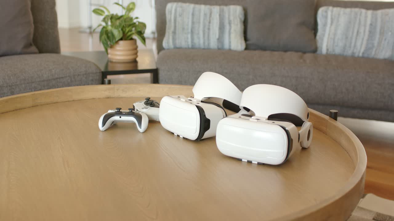 Camera is zooming in, highlighting two VR headsets and controller on coffee table in living room