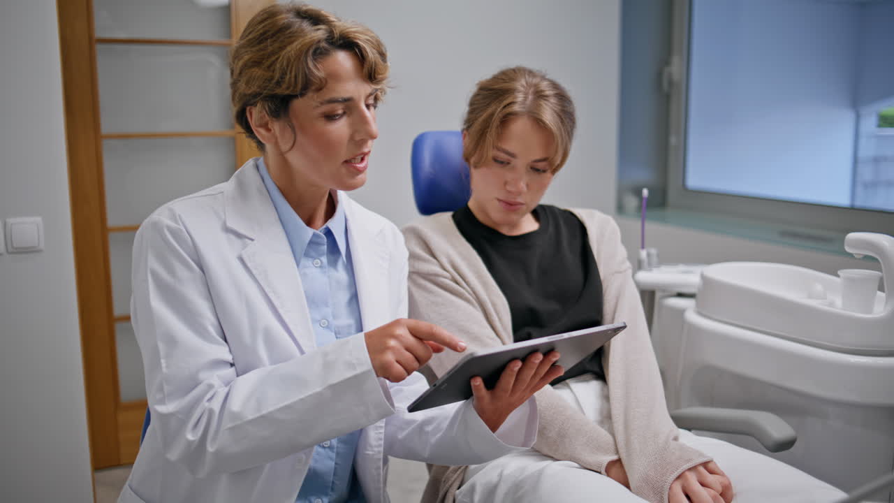 Woman dentist demonstrating tablet with treatment plan to patient clinic closeup