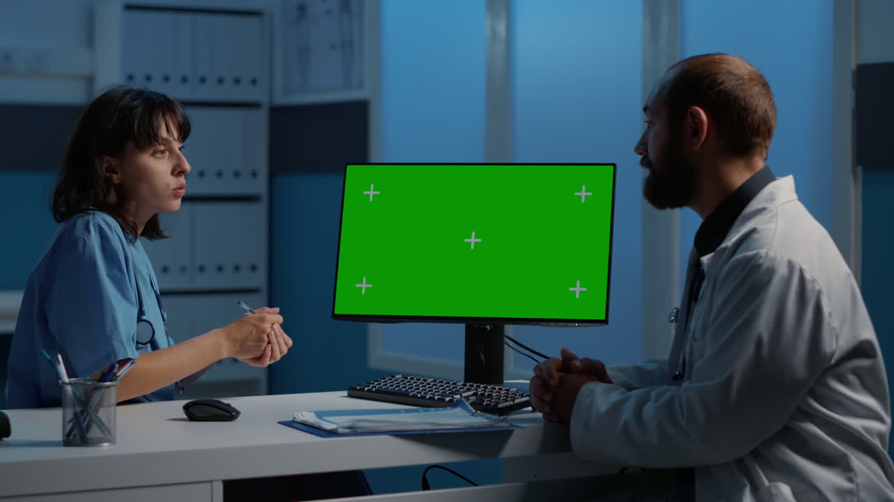 Medical professionals discussing patient care using a computer with a green screen