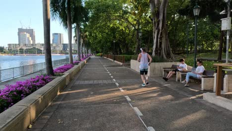 a jogger runs past people sitting on a bench.