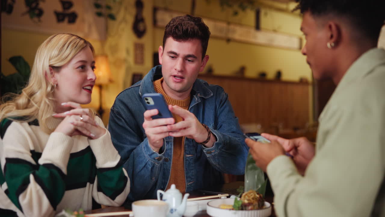 Friends gathering at a restaurant, using phones