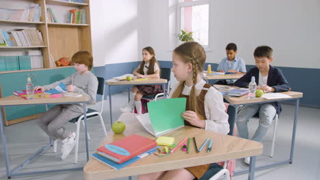 Multiethnic-Group-Of-Kids-In-Classroom-Opening-The-Notebooks-During-English-Class