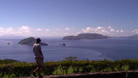 Male-solo-traveler-looking-out-towards-beautiful-blue-ocean-and-islands-on-clear-and-sunny-day