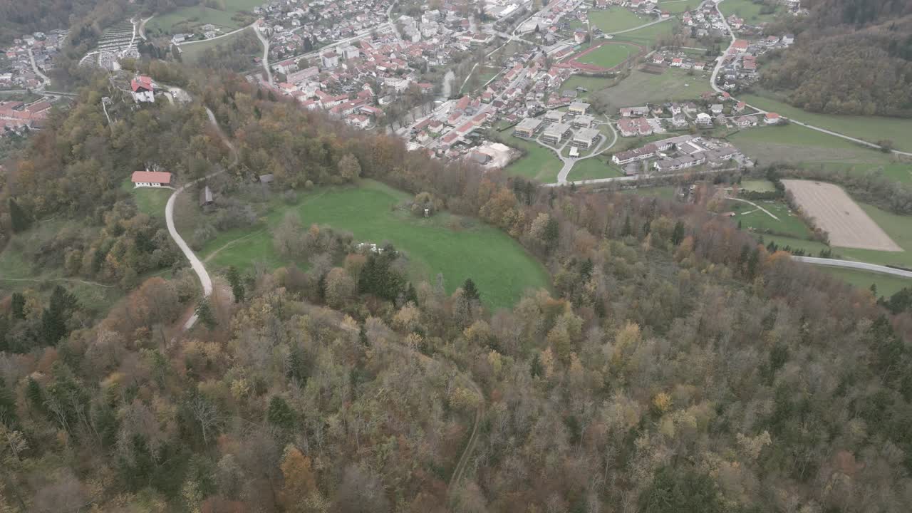 Aerial View of a Small Town Surrounded by Forests and Hills in Autumn