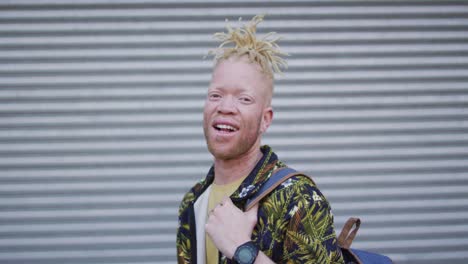 portrait of smiling albino african american man with dreadlocks looking at camera