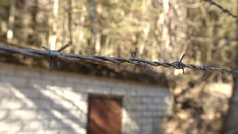 una cuerda afilada de alambre de púas frente a un edificio demolido, cerca con movimiento de plataforma rodante
