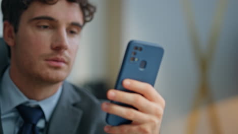 attractive man reading smartphone sitting at buro closeup. ceo surfing internet