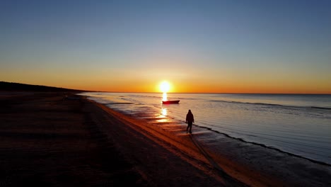 Eine-Frau-Mit-Sicherem-Schritt,-Der-Sonnenuntergang-Wirft-Lange-Schatten,-Entlang-Der-Küste-Des-Meeres,-Person,-Die-Bei-Sonnenuntergang-Am-Strand-Spazieren-Geht